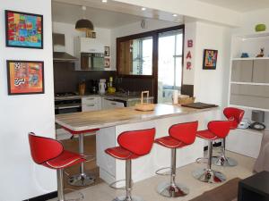 kuchnia z czerwonymi stołkami barowymi i blatem w obiekcie Apartment Le Paradou by Interhome w mieście Virebelle