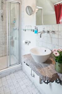 a white bathroom with a sink and a shower at Hotel Der Grischäfer in Bad Emstal
