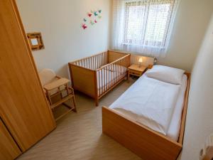 DittishausenにあるHoliday Home Rheingau by Interhomeのベビーベッド、ベッド、窓が備わる小さな客室です。