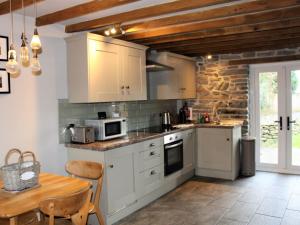 a kitchen with white cabinets and a table and a counter at Holiday Home Winill by Interhome in Llanddewi-Brefi