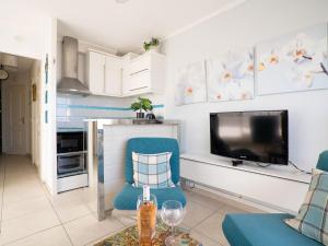 een woonkamer met een blauwe stoel en een televisie bij Apartment Cap Sud-3 by Interhome in Canet-en-Roussillon