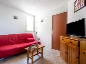 - un canapé rouge dans le salon doté d'une télévision à écran plat dans l'établissement Apartment Le Beach-14 by Interhome, à Canet
