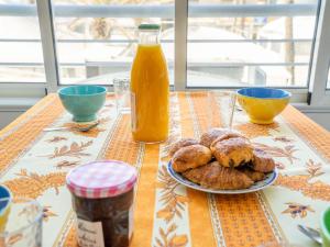 una mesa con un plato de bollería y una botella de zumo de naranja en Apartment Le Sunset-Cap Sud-1 by Interhome, en Cap d'Agde