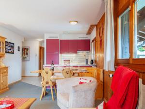 eine Küche mit roten Schränken sowie einem Tisch und Stühlen in der Unterkunft Apartment Les Crêtes 1-3 by Interhome in Veysonnaz