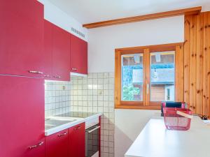 a kitchen with red cabinets and a window at Apartment Les Crêtes 1-3 by Interhome in Veysonnaz +28 photos