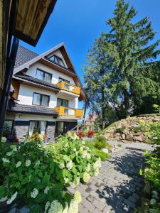 a building with a tree and flowers in front of it at Baca in Bukowina Tatrzańska