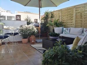eine Terrasse mit einem Sofa und einem Sonnenschirm in der Unterkunft Sol y Malaga - Designer Duplex con Terraza y Parking in Málaga