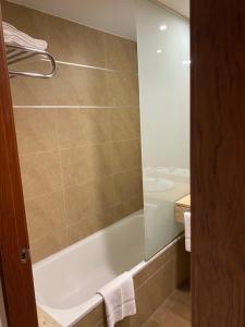 a bathroom with a tub and a shower with a mirror at Cityexpress Hotel San Fernando - Carcaixent 