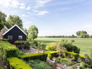 een zwart huis met een tuin voor een veld bij Holiday Home Tuinzicht by Interhome in Zuid-Beijerland