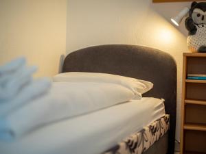 un letto con lenzuola bianche e un animale di peluche su una mensola di Apartment F 55 by Interhome a Dittishausen