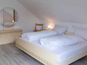 1 Schlafzimmer mit 2 Betten mit weißer Bettwäsche und einem Spiegel in der Unterkunft Apartment Hochfirst by Interhome in Dittishausen