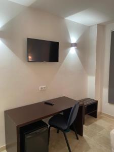 a room with a desk and a television on a wall at Cityexpress Hotel San Fernando - Carcaixent 