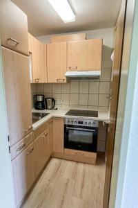 een keuken met houten kasten en een kookplaat met oven bij Apartment Schwarzwaldblick-14 by Interhome in Schonach +9 foto's