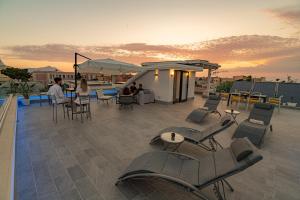 a rooftop patio with chairs and tables and a building at CALLIA ROOMS PROCIDA in Procida