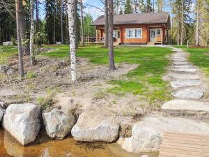 eine Blockhütte im Wald mit einem Weg und Bäumen in der Unterkunft Holiday Home Nesterin helmi by Interhome in Eno