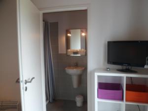 a bathroom with a sink and a tv and a mirror at Hotel du Cap in Cap-Ferret