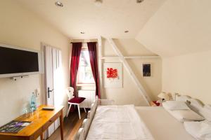 1 dormitorio con 1 cama, escritorio y TV en Hotel Der Grischäfer, en Bad Emstal