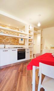 a kitchen with white cabinets and a red table and chairs at Gurgiolo New Apartment in Trabia