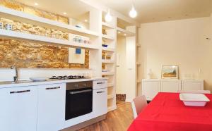 a kitchen with white cabinets and a table with a red rug at Gurgiolo New Apartment in Trabia