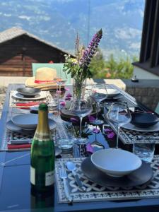 a table with plates and glasses and a bottle of wine at Chalet Familial Capricorne in Vercorin