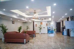 eine Lobby mit braunen Sofas und einer weißen Wand in der Unterkunft Hotel Leaf studio Medicity in Gurgaon