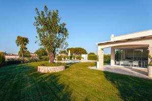 a house with a tree in the middle of a yard at HelloApulia Villa Capitolo Beach in Monopoli