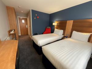 um quarto de hotel com duas camas e uma cadeira vermelha em Holiday Inn Express Nuneaton, an IHG Hotel em Nuneaton