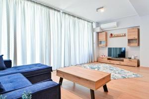 Cozy apartment located on Piraeus Port area-(SPETS_D1) في بيرايوس: غرفة معيشة مع أريكة زرقاء وطاولة