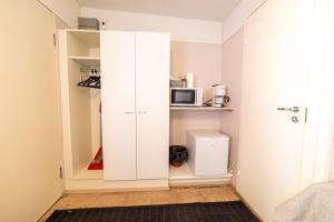 a white cabinet in a small room with a microwave at Rantakallan Rinne rivitalohuoneet in Kalajoki