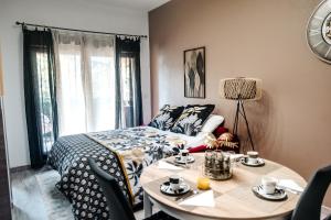 een slaapkamer met een bed en een tafel met stoelen bij Appartement moderne central avec piscine, garage privé et terrasse sud in Uzès