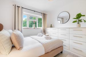 a white bedroom with a bed and a mirror at Modern 1 bed-Nr Warner Bros-Parking-Garden in Watford