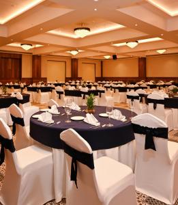 a banquet hall with tables and white chairs at Effotel by Sayaji Sarola in Bhor