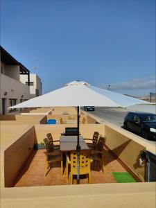 einen Tisch und Stühle unter einem Regenschirm auf dem Dach in der Unterkunft COTILLO BEACH SUN in Cotillo