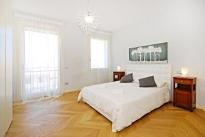 a white bedroom with a large bed and a chandelier at Riverside Apartment in Treviso