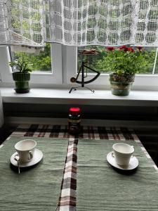 zwei Tassen auf einem Tisch vor einem Fenster in der Unterkunft Cosy house with forest view in Pyussi