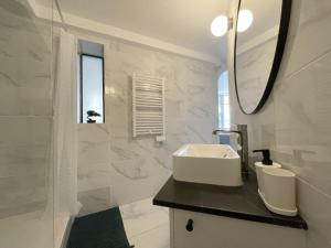 uma casa de banho branca com um lavatório e um espelho em La Bohème em Romainville