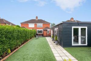 a garden with a black house and green grass at Modern home 10 mins to Belfast City in Belfast