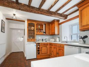 uma cozinha com armários de madeira e um frigorífico branco em Characterful 3 Bedroom Cottage em Aberystwyth