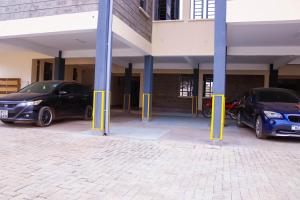 two cars parked in a parking lot with blue poles at BASICS HOME STAYS in Nairobi