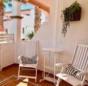 dwa krzesła i stół na balkonie w obiekcie Casa El Faro w mieście El Rompido