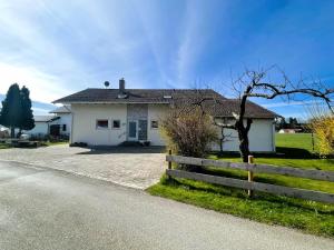 a white house with a fence on the side of a road at CASA LOBO Charmantes Ferienhaus im Allgäu in Leutkirch im Allgäu