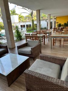 a patio with tables and wicker chairs and tables at Apart Hotel Delphin Guaruja in Guarujá