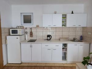 a white kitchen with white cabinets and a microwave at Apartment Lilac Sarajevo in Sarajevo