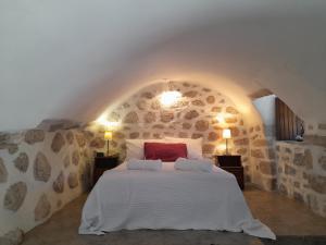 1 dormitorio con 1 cama grande en una pared de piedra en The Two Carob Trees, Traditional Stonehouse, Nikandri, Pirgos Diros en Levkiás