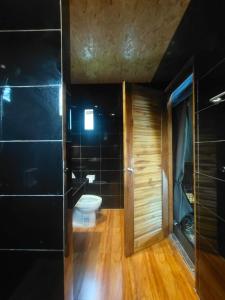 a bathroom with a toilet and a black wall at Country Cafe & Camping in Ban Cha-om
