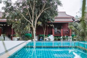 a swimming pool in front of a house with a building at Country Cafe & Camping in Ban Cha-om