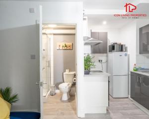 a bathroom with a toilet and a sink and a refrigerator at Arch-View Apartment 1 By Icon Living Properties Short Lets & Serviced Accommodation Wembley in London