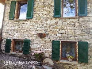 un edificio de piedra con persianas verdes. en Segarati Relax La Romantica, en Rocca di Varsi