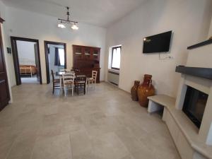 un soggiorno con tavolo, sedie e televisione di L'Humus dei Trulli holiday house a Martina Franca