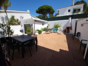 a wooden deck with a table and chairs on it at ALOJAMENTO -GUEST HOUSE - Caparica - Trafaria - Surf Sun and Lisbon Lovers in Trafaria